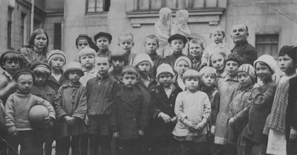 Фотография во дворе дома на фоне корпуса художественных мастерских. Тамара Кузнецова стоит справа от мальчика с мячом в шляпке и в пальто с крупными пуговицами. Предположительно автор фотоснимка отец Тамары Иван Макарович Кузнецов. По воспоминаниям Натальи Саркисьянц, он увлекался фотографией. 13 мая 1931 года